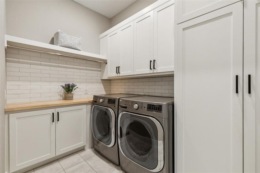 Laundry room featuring light tile patterned floors, cabinets, and washer and clothes dryer