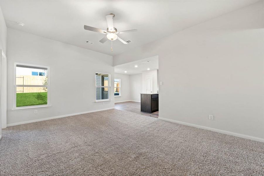 Unfurnished living room featuring ceiling fan and light colored carpet