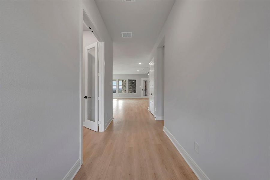 Hallway with light wood finished floors and recessed lighting