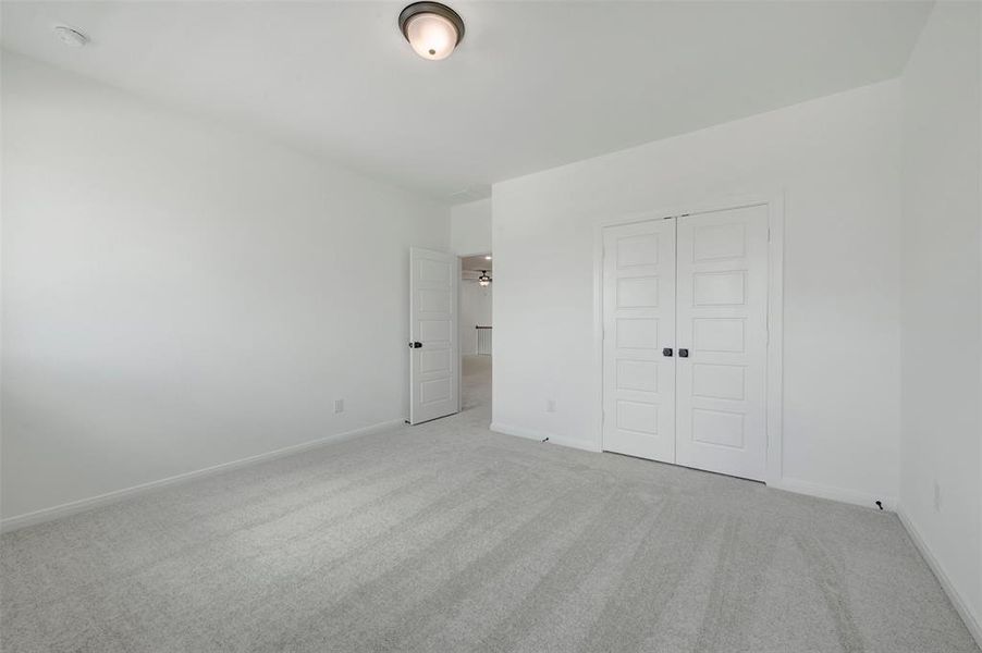 Spacious room featuring light gray carpet flooring, white walls, and a ceiling-mounted light fixture Spacious room featuring light gray carpet flooring, white walls, and a ceiling-mounted light fixture