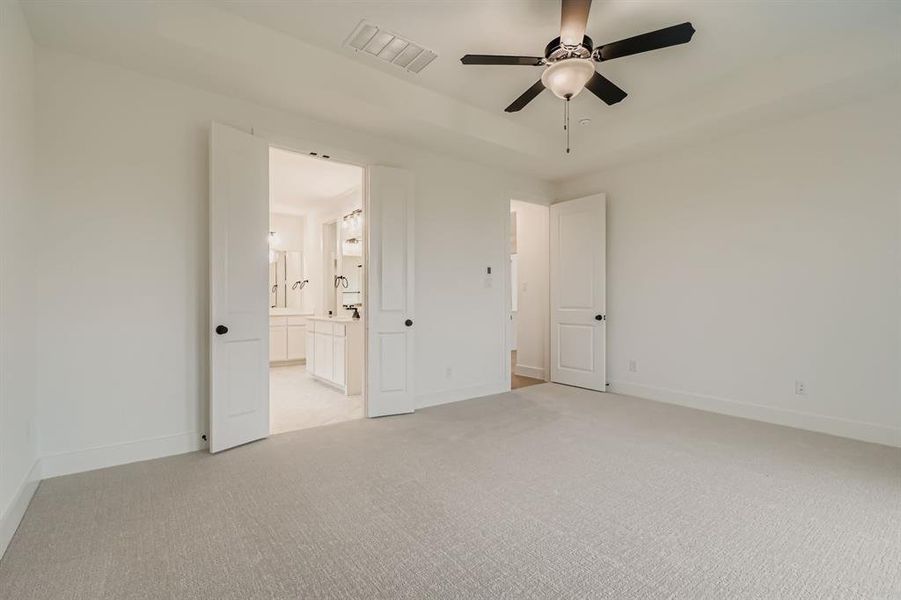 Unfurnished bedroom featuring light colored carpet, a ceiling fan, and connected bathroom Unfurnished bedroom featuring light colored carpet, a ceiling fan, and connected bathroom