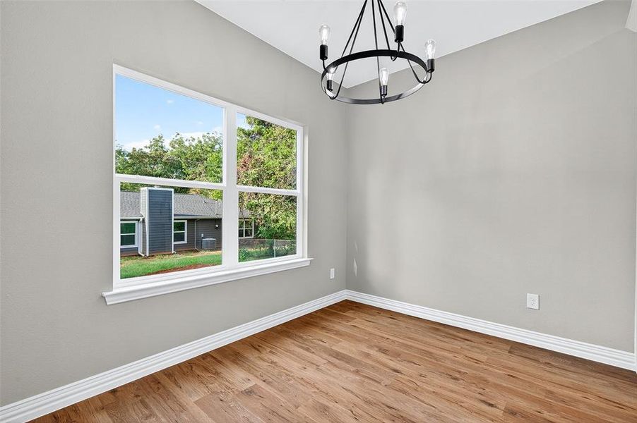 Unfurnished room with light wood-style flooring and a chandelier Unfurnished room with light wood-style flooring and a chandelier
