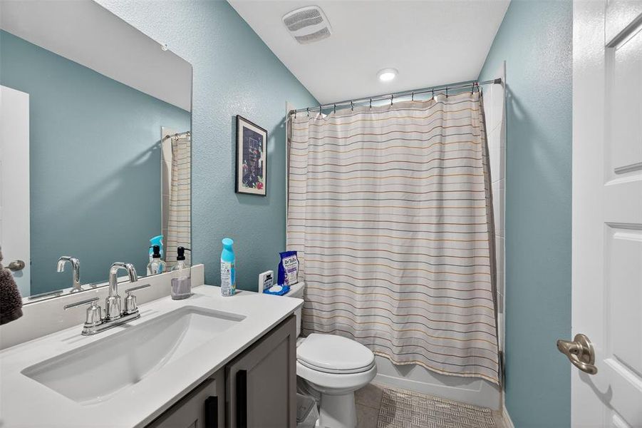Bathroom with vanity, a textured wall, and shower / bath combination with curtain