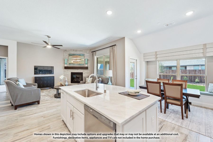Open-concept kitchen with white island, quartz countertops, and view into living and dining areas with stone fireplace. Open-concept kitchen with white island, quartz countertops, and view into living and dining areas with stone fireplace.