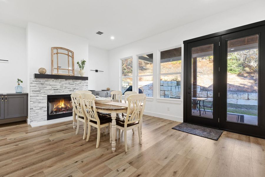 Dining area with light wood-style flooring, recessed lighting, and a stone fireplace