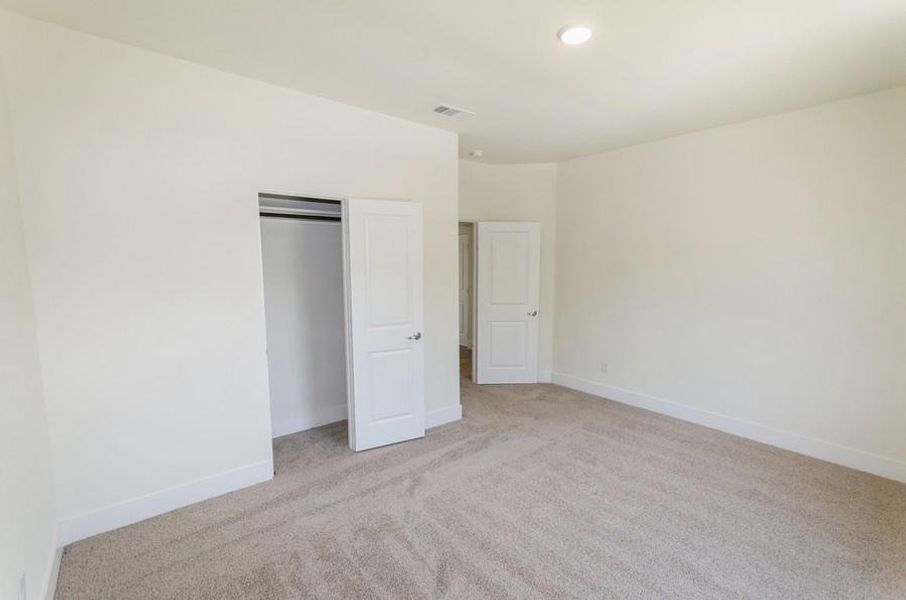 Unfurnished bedroom featuring a closet and light colored carpet