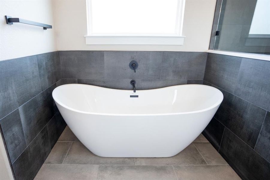 Bathroom featuring a freestanding bath, healthy amount of natural light, tile walls, and tile patterned floors Bathroom featuring a freestanding bath, healthy amount of natural light, tile walls, and tile patterned floors