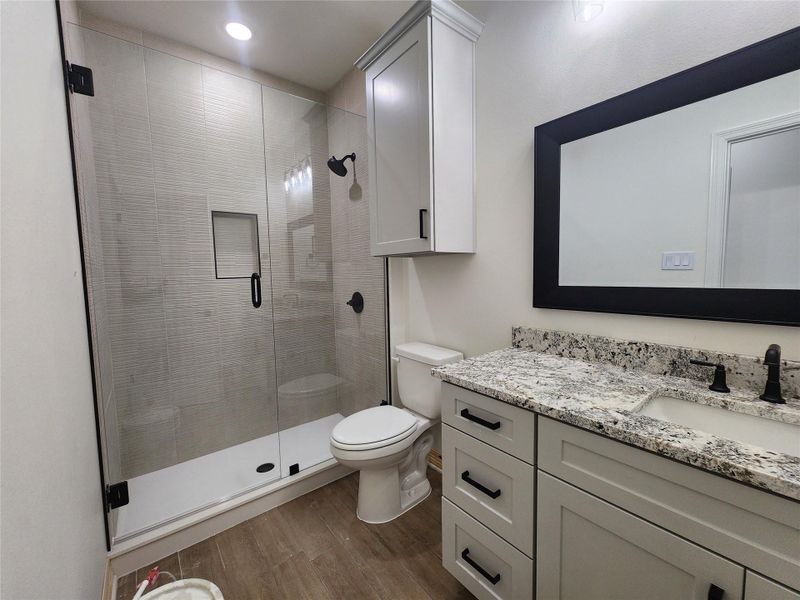 Bathroom featuring a glass-enclosed shower with textured tile, white shower base, built-in shower niche, and matte black fixtures