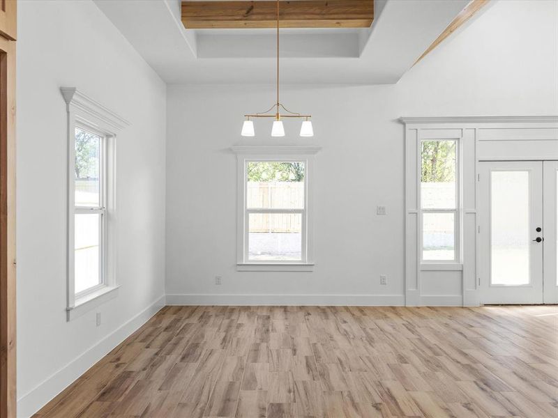 Unfurnished dining area with light wood-style floors, healthy amount of natural light, and a raised ceiling