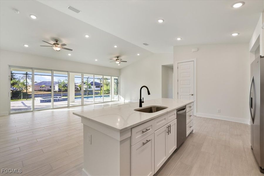 Kitchen with open floor plan, lofted ceiling, recessed lighting, white cabinets, and wood finish floors