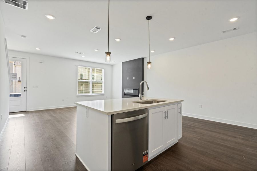 Open-concept living space featuring wood-finish flooring, recessed lighting, and a kitchen island with an integrated sink and dishwasher Open-concept living space featuring wood-finish flooring, recessed lighting, and a kitchen island with an integrated sink and dishwasher