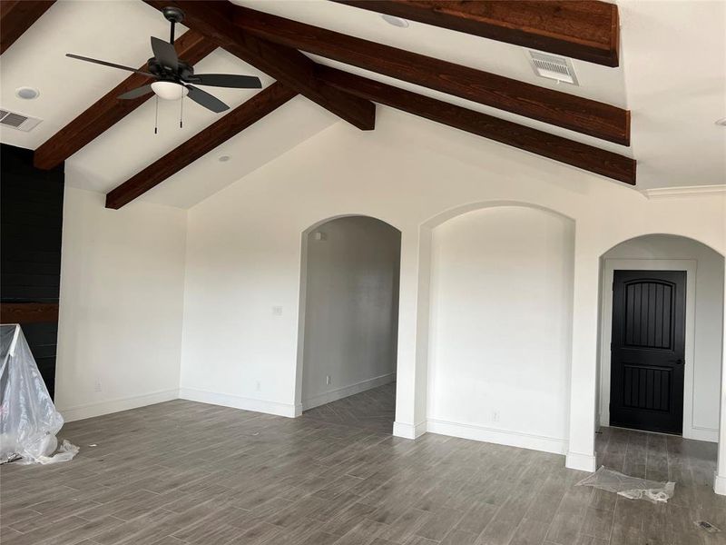 Unfurnished living room featuring wood finish floors, arched walkways, and a ceiling fan