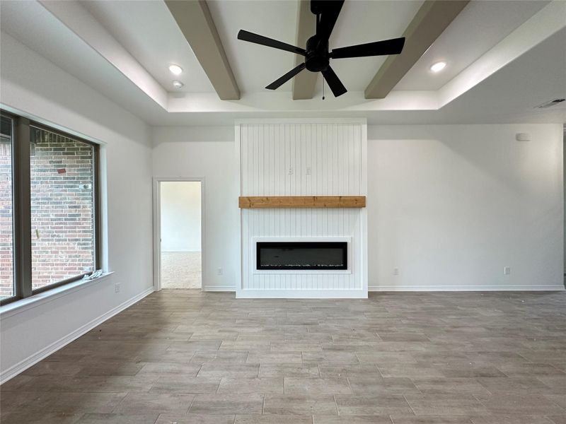 Living space featuring a tray ceiling with recessed lighting, exposed ceiling beams, and a black ceiling fan