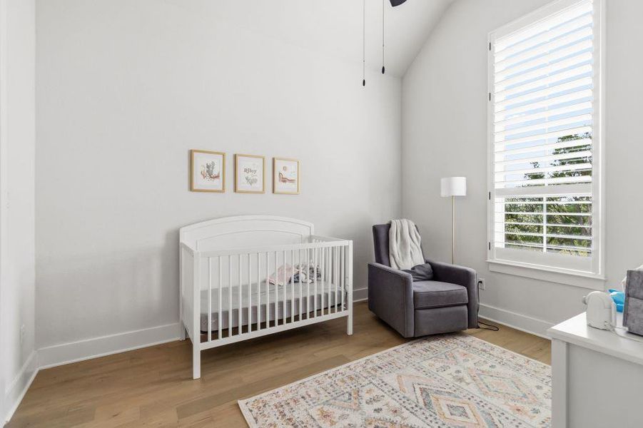 Naturally illuminated, this nursery space features vaulted ceilings and light wood flooring.