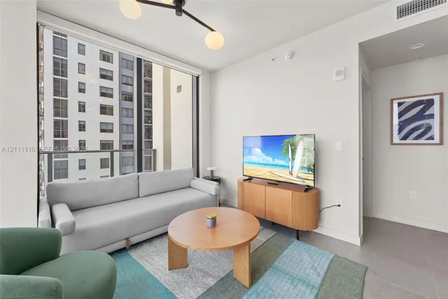 Floor-to-ceiling windows, modern multi-arm ceiling light fixture, neutral wall finishes, and ceramic tile flooring