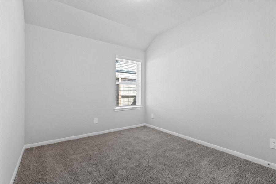 This cozy secondary bedroom offers plush soft carpeting, neutral walls ready for personalization, a sun-filled window with fitted blinds, sloped ceilings, and a spacious closet for all your storage needs.