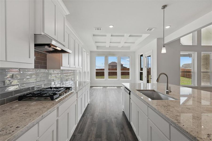 Kitchen featuring coffered ceiling, visible vents, stainless steel appliances, a sink, and backsplash