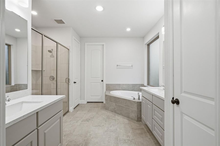 This is a spacious, modern bathroom featuring a large walk-in shower, a separate bathtub, and dual vanities with ample storage. The light, neutral tones create a clean and inviting atmosphere. This is a spacious, modern bathroom featuring a large walk-in shower, a separate bathtub, and dual vanities with ample storage. The light, neutral tones create a clean and inviting atmosphere.