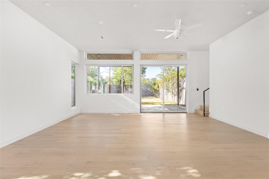 Unfurnished room with healthy amount of natural light, light wood-style flooring, stairs, ceiling fan, and recessed lighting