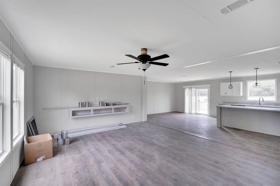 Open-concept interior featuring wood-finish flooring, light gray walls, a ceiling fan, and sliding glass doors