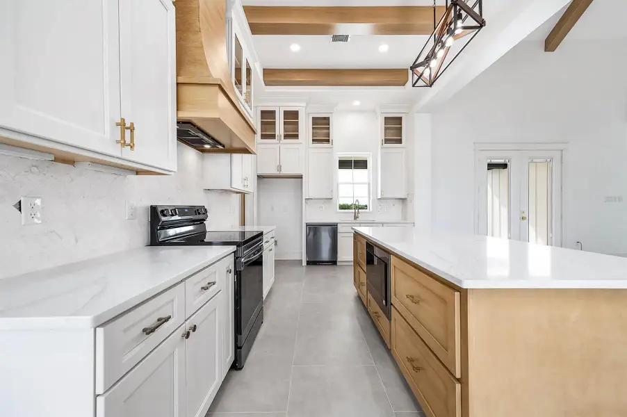 Another view of the kitchen highlighting the oversized island, custom cabinetry, and warm wood details throughout.