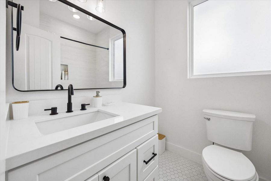 Second full bath keeps the black fixtures going, with a wide vanity, framed mirror, and hex tile underfoot. Second full bath keeps the black fixtures going, with a wide vanity, framed mirror, and hex tile underfoot.