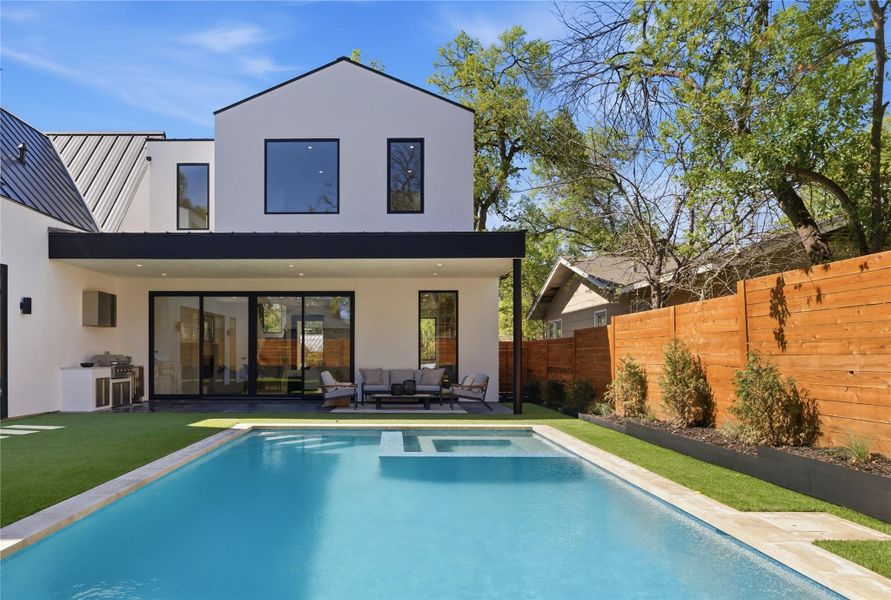 Back of property with a patio area, stucco siding, a fenced backyard, and a pool with connected hot tub