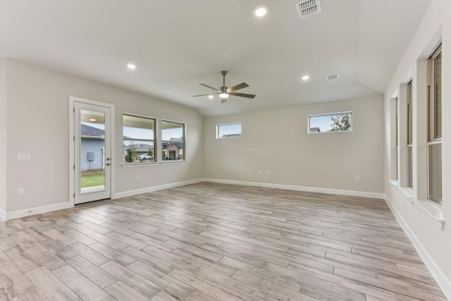 Spare room featuring plenty of natural light, recessed lighting, wood tiled floors, ceiling fan, and vaulted ceiling