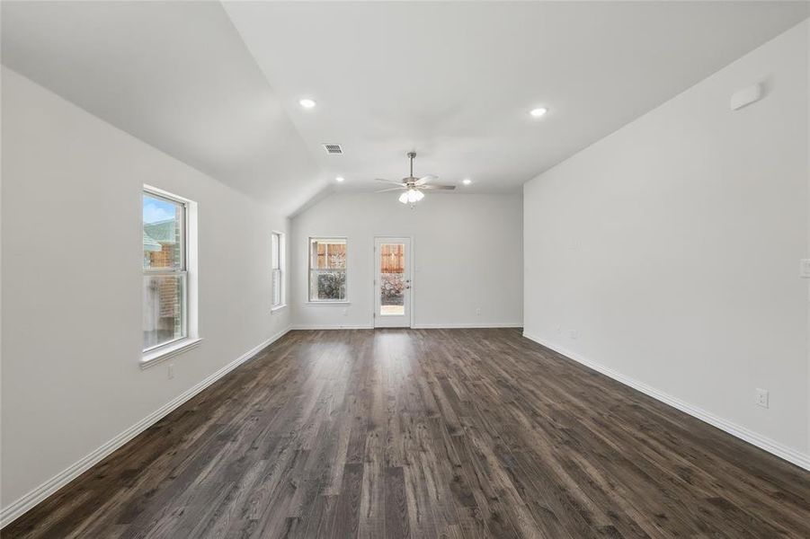 Unfurnished living room with dark wood-type flooring, visible vents, baseboards, and a ceiling fan