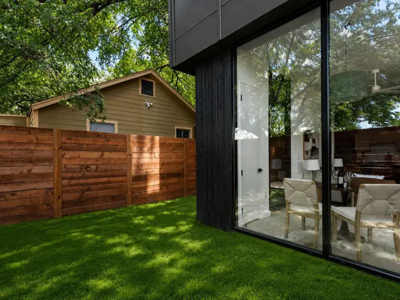 A well-maintained lawn and sturdy wood privacy fence border a modern structure with expansive glass. A well-maintained lawn and sturdy wood privacy fence border a modern structure with expansive glass.