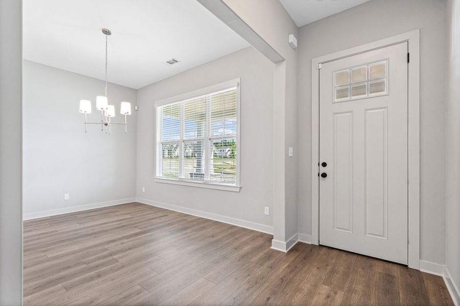 Entryway with wood-finish flooring, a white door featuring decorative glass panels, and a modern chandelier