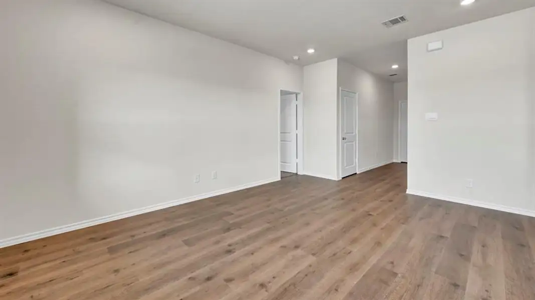 Spacious interior featuring wood-finish flooring, recessed lighting, white walls, and white baseboards