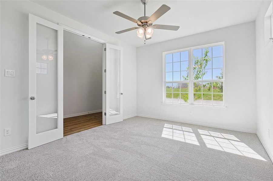 Unfurnished bedroom with carpet, ceiling fan, and french doors