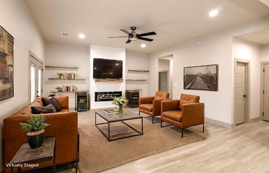 Living room with light wood-style floors, a glass covered fireplace, recessed lighting, and ceiling fan