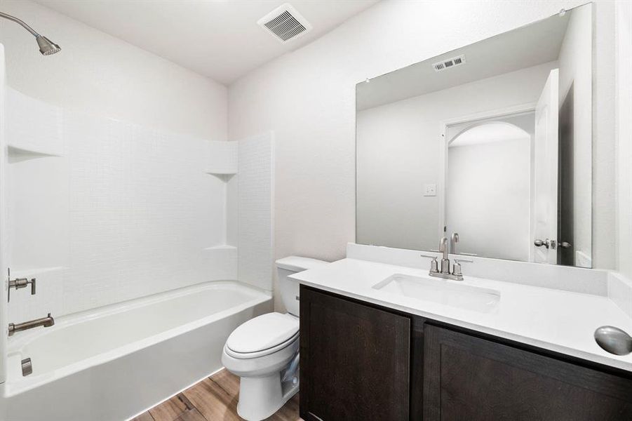 Full bathroom with toilet, hardwood / wood-style floors, shower / bathtub combination, and vanity