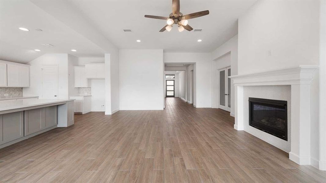 Unfurnished living room featuring a fireplace, light wood-type flooring, and ceiling fan