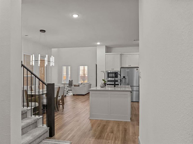 Kitchen featuring stainless steel appliances, white cabinetry, a center island, light hardwood / wood-style floors, and pendant lighting