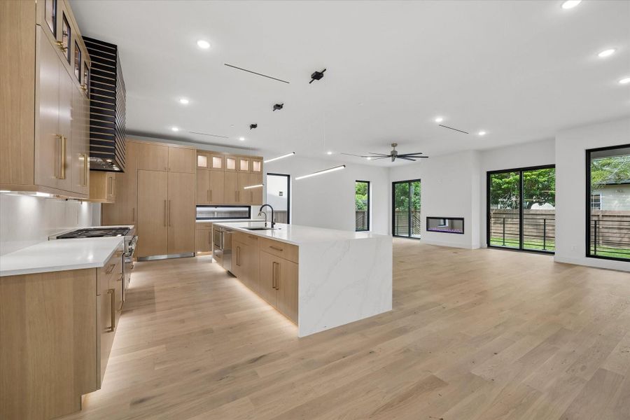 Base lighting helps float the kitchen cabinetry. The quartz countertop at the island has a waterfall edge.