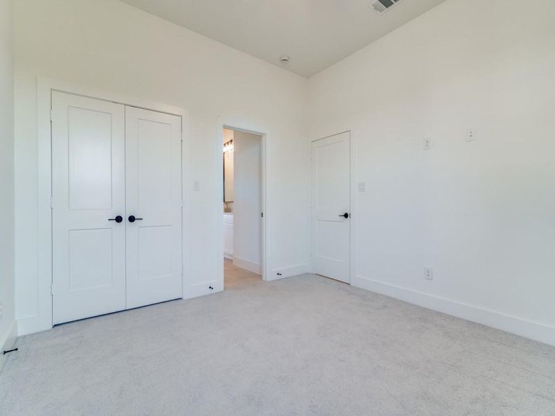 Unfurnished bedroom with light carpet, a closet, and connected bathroom