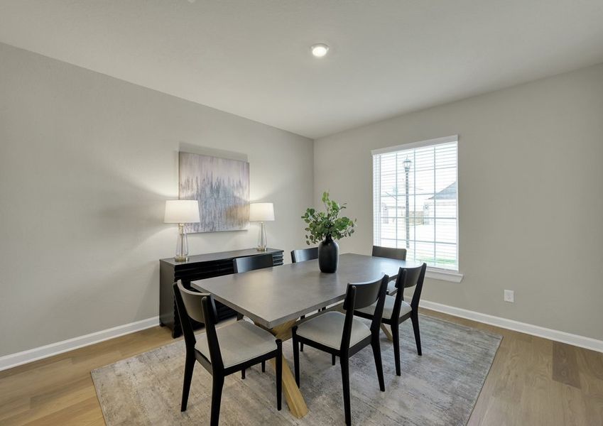 Dining room featuring a dark wood table with seating for six, framed artwork, and wood-look flooring.