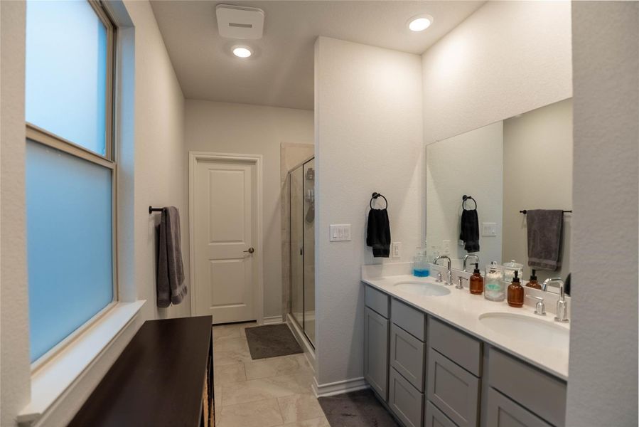 Bathroom featuring a stall shower, double vanity, and light tile patterned floors Bathroom featuring a stall shower, double vanity, and light tile patterned floors