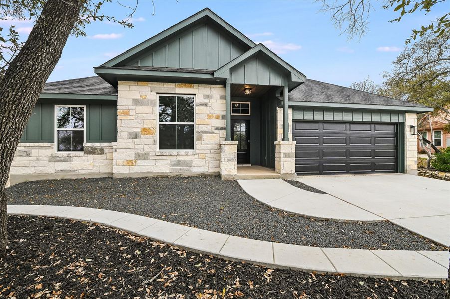 View of front of property with board and batten siding, concrete driveway, a shingled roof, and a garage