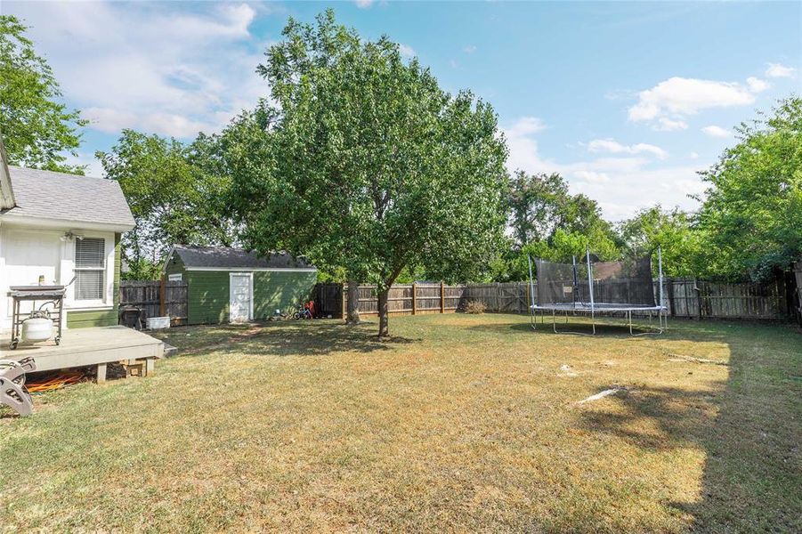 Fenced backyard with a storage shed and a trampoline Fenced backyard with a storage shed and a trampoline