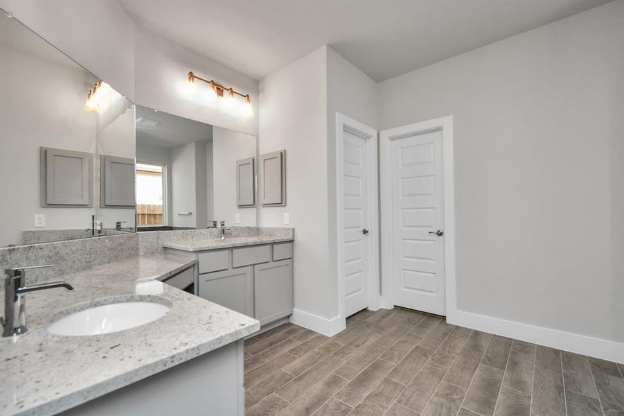 Full length mirrors, double sinks, modern vanity lights, and sleek hardware make this primary bathroom a sophisticated oasis of contemporary elegance and functionality. Sample photo of completed home with similar plan. As built color and selections will vary.