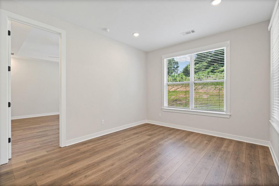 Room featuring wood-finish flooring, recessed lighting, and a window with horizontal blinds Room featuring wood-finish flooring, recessed lighting, and a window with horizontal blinds