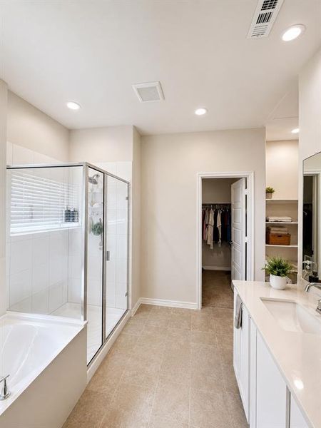 Spacious bathroom featuring a glass-enclosed shower, separate soaking tub, and a dual vanity with a light-toned countertop
