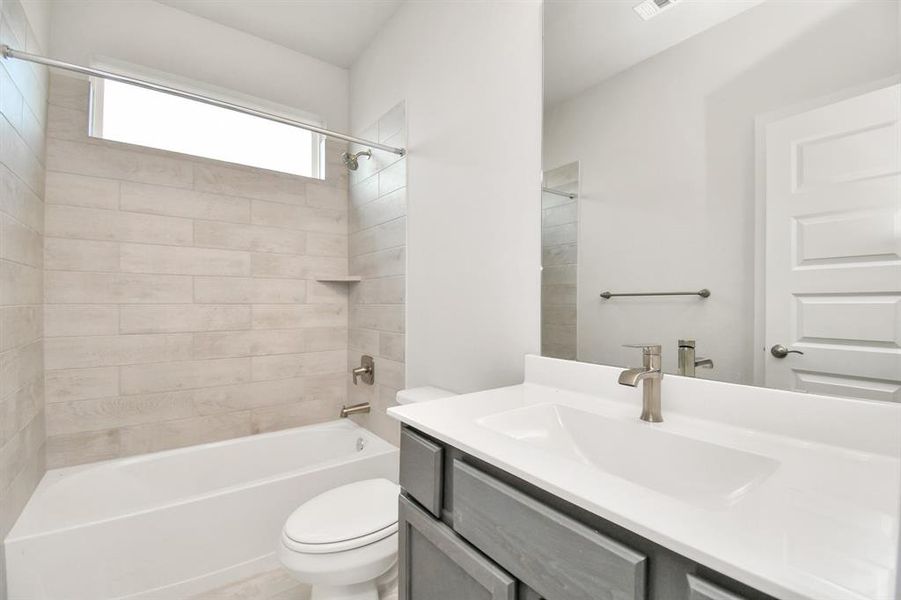 Experience sophistication in the secondary bathroom, where tile flooring complements a bath/shower combo with tile surround. Light wood cabinets complete with a beautiful light countertop, enhances the space for a truly inviting ambiance.