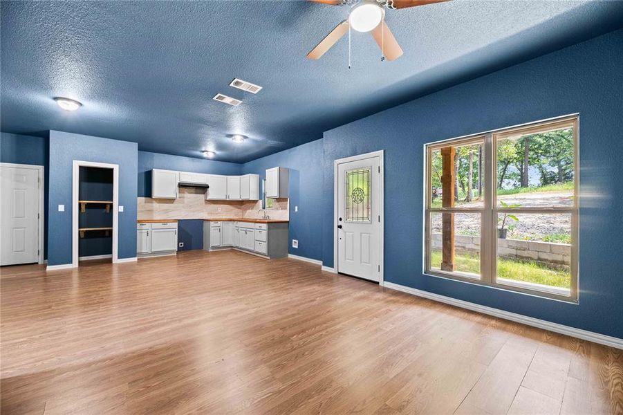 Unfurnished living room featuring ceiling fan, light hardwood / wood-style flooring, and a textured ceiling Unfurnished living room featuring ceiling fan, light hardwood / wood-style flooring, and a textured ceiling
