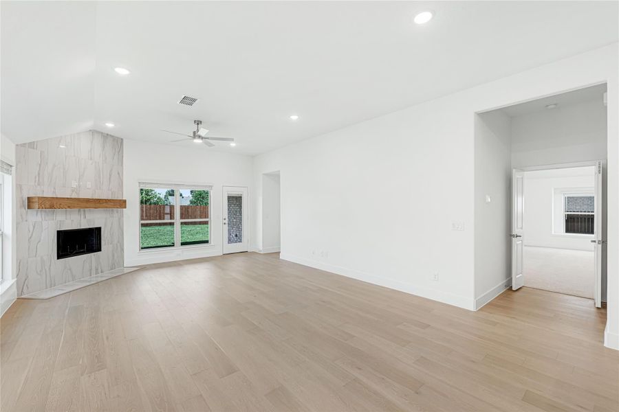 Open living room with tile fireplace, wood mantel, hardwood floors, and sliding glass door to backyard