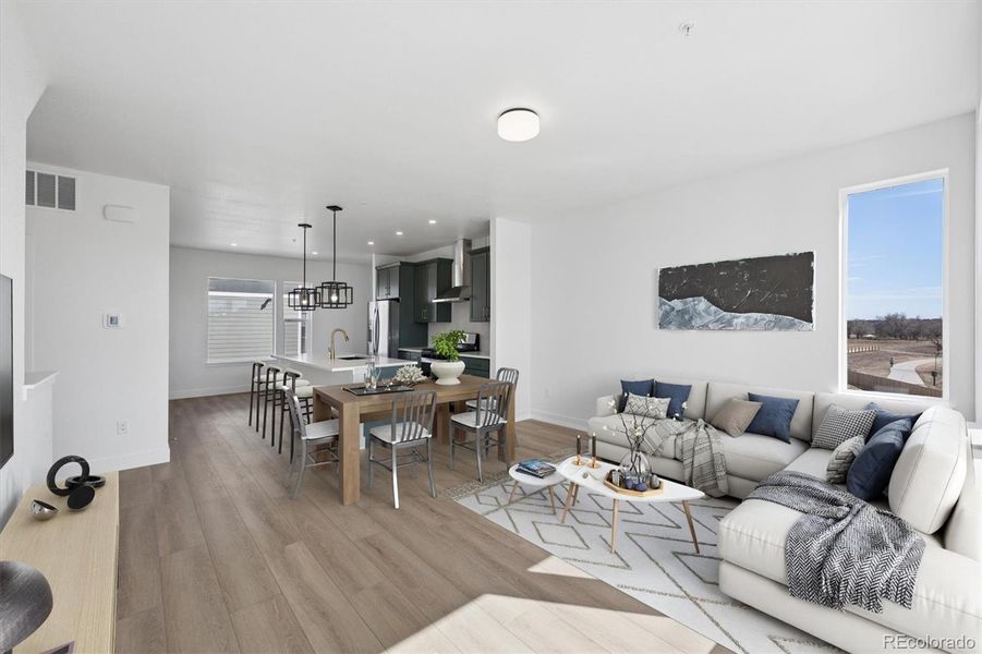 Bright and open main living area featuring wide-plank flooring, expansive windows, and seamless flow between the living, dining, and kitchen spaces. Virtually Staged. Bright and open main living area featuring wide-plank flooring, expansive windows, and seamless flow between the living, dining, and kitchen spaces. Virtually Staged.